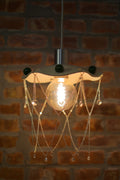 Decorative pendant light with hanging chandelier crystals against a brick wall.